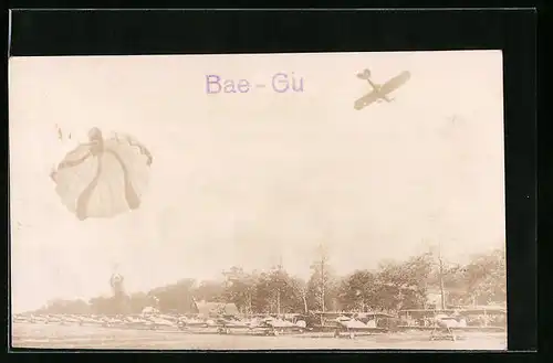 Foto-AK Fallschirmjäger landet auf dem Flugfeld mit in Startposition gebrachten Doppeldeckern