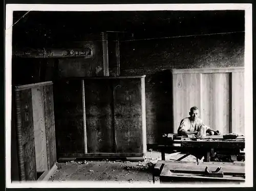 Fotografie Möbel-Tischler bei der Arbeit an der Hobelbank, fertige Schränke stehen in der Werkstatt