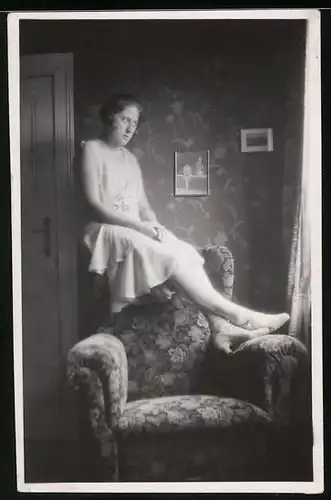 Fotografie junge Dame im Abendkleid auf Sessel unkonventionell sitzend