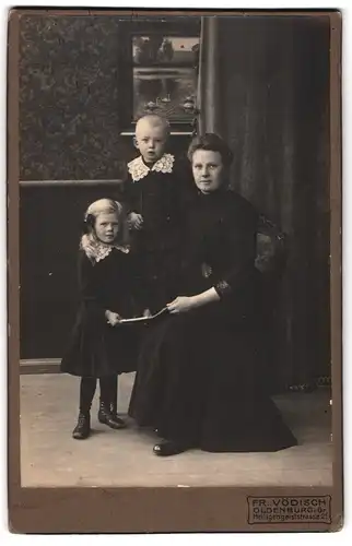 Fotografie Fr. Vödisch, Oldenburg i. G., Heiligengeiststr. 2, Junge Dame im Kleid mit zwei Kindern