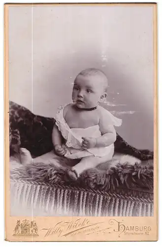 Fotografie Willy Wilcke, Hamburg, Steindamm 62, Halbnacktes Kleinkind im Hemd sitzt auf Fell