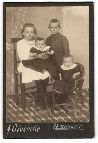 Fotografie A. Giesecke, Hannover, Mädchen im weissen Kleid und Junge mit zwei Kleinkindern