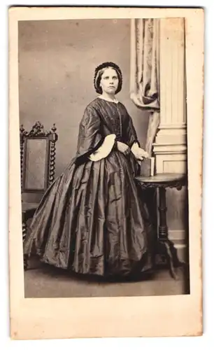 Fotografie unbekannter Fotograf und Ort, junge Frau im seidenen Biedermeierkleid mit Haube posierend