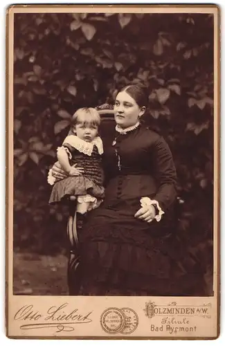 Fotografie Otto Liebert, Holzminden a. W., Mutter im dunklen Biedermeierkleid mit ihrer Tochter im Arm, Mutterglück