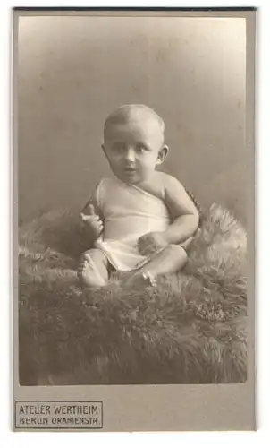 Fotografie Atelier Wertheim, Berlin, Oranienstr., Portrait süsses Baby im Hemdchen auf Fell sitzend