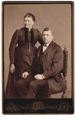Fotografie F. Heiler, Osnabrück, Alte Frau mit Flechtfrisur und Mann im Dreiteiler