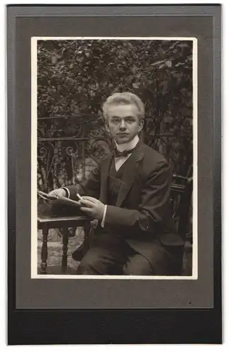Fotografie unbekannter Fotograf und Ort, Junger Mann im Dreiteiler, in einem Garten sitzend