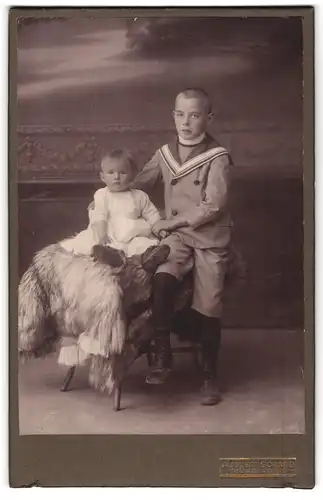 Fotografie August Schmid, Münsingen, Junge im Matrosenanzug mit Kleinkind auf Fell