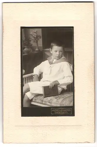 Fotografie Alfred Schaffer, Saalfeld a /S., Junger Mann im Matrosenanzug mit einem Buch