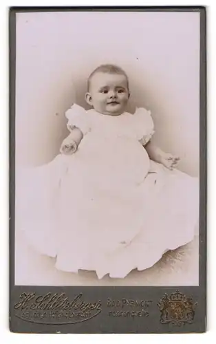 Fotografie H. Schlitzberger, Bad Pyrmont, Helenenquelle, Lächelndes Baby im Taufkleid