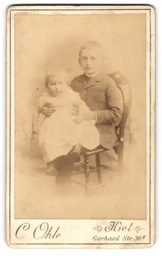 Fotografie C. Ohle, Kiel, Gerhardstr. 30, Junger Mann im Anzug mit Kleinkind auf dem Schoss