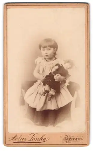 Fotografie Atelier Lonke, Meissen a. E., Portrait süsses Mädchen im Kleidchen hält grosse Puppe im Arm