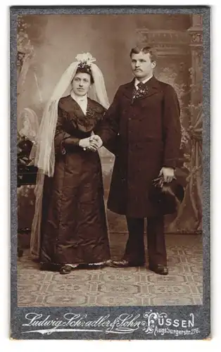 Fotografie Ludwig Schradler & Sohn, Füssen, Eheleute im schwarzen Hochzeitskleid und Anzug mit Zylinder