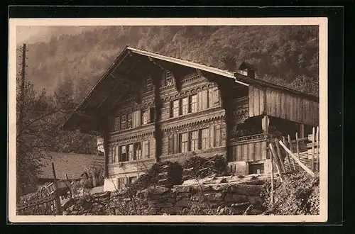 AK Niederried /Brienzer See, Schweizer Bauernhaus mit Holzstapeln