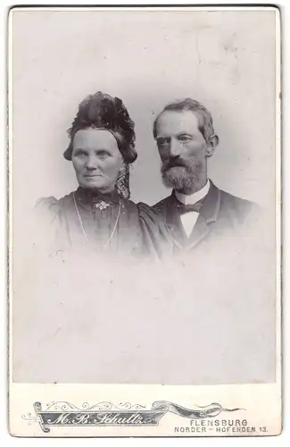 Fotografie M. B. Schultz, Flensburg, Norder-Hofenden 13, Älteres Paar in hübscher Kleidung