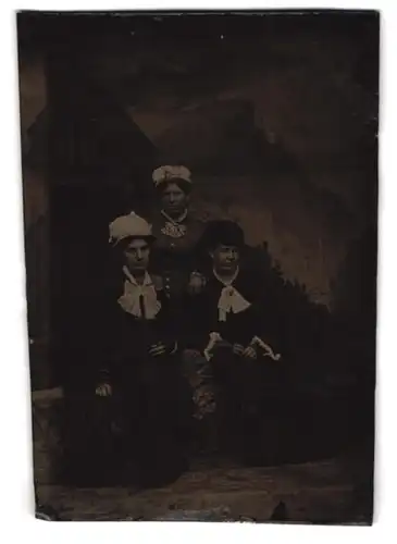 Fotografie Ferrotypie drei junge Damen in Biedermeierkleidern mit Hüten vor einer Studiokulisse