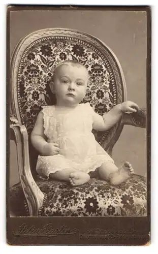 Fotografie Atelier Gustin, Stockholm, Drottningg 93, Kleinkind im weissen Kleidchen auf einem Stuhl