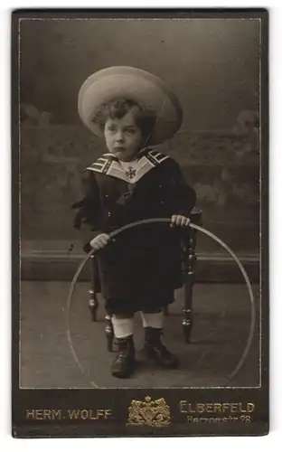 Fotografie Herm. Wolff, Elberfeld, Herzogstr. 28, Kleiner Junge in modischer Kleidung mit Reifen