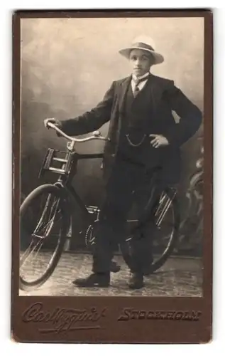 Fotografie Carl Nyquist, Stockholm, Portrait junger Mann im Anzug posiert im Atelier mit seinem Fahrrad