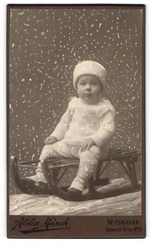 Fotografie Atelier Münch, Wiesbaden, Bismarck-Ring 21, kleiner Knabe auf seinem Schlitten in Winterkleidung, Schnee