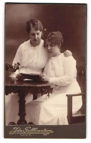 Fotografie Ida Gullbrantson, Lund, Stortorget 4, Zwei weiss gekleidete Damen mit einem Buch