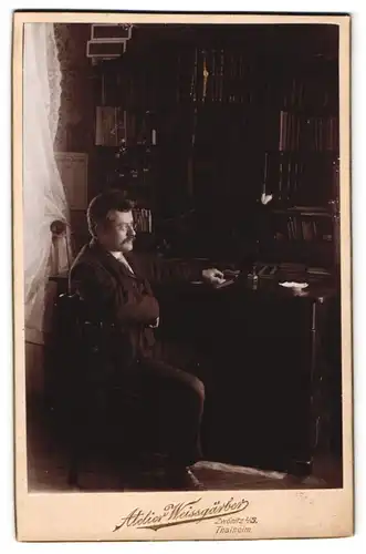 Fotografie Atelier Weissgärber, Zwönitz i. Sa., Herr sitzt an seinem Schreibtisch mit Bücherregalt