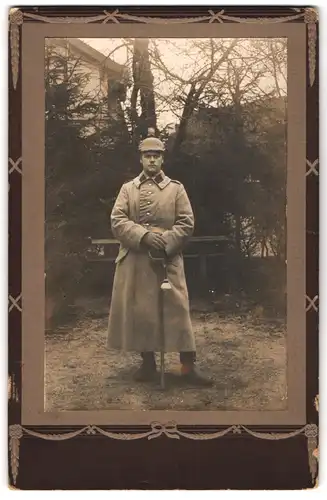 Fotografie Fotograf und ort unbekannt, Portrait Soldat im Uniformmantel mit Artillerie Pickelhaube Tarnbezug und Säbel