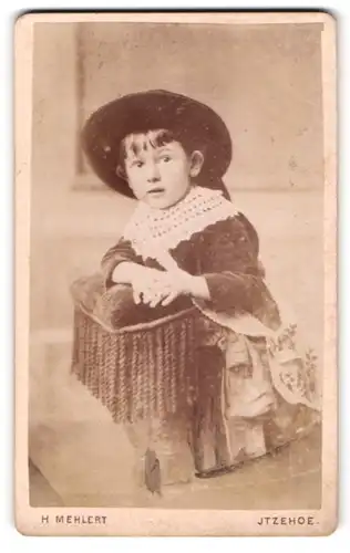 Fotografie H. Mehlert, Itzehoe, Breitestrasse 14, Kleines Kind mit Hut, auf einen Hocker gestützt