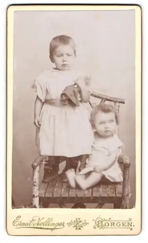 Fotografie Ernst Zollinger, Horgen, Zwei kleine Mädchen mit Puppe auf einem Stuhl