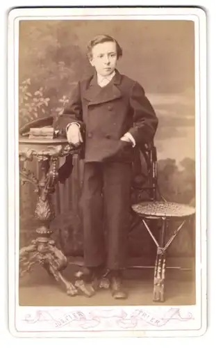Fotografie Jos. Fier, Trier, Brückenstr. 44, Portrait eines elegant gekleideten Buben am Tisch stehend