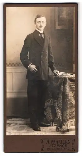 Fotografie A. Martens, Itzehoe, Mühlenstr. 5-7, Portrait elegant gekleideter Bube am Tisch stehend