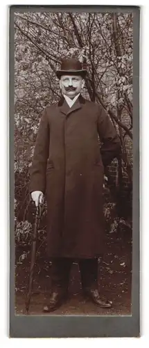 Fotografie unbekannter Fotograf und Ort, Portrait stattlicher Herr mit Flanierstock und Hut im Mantel