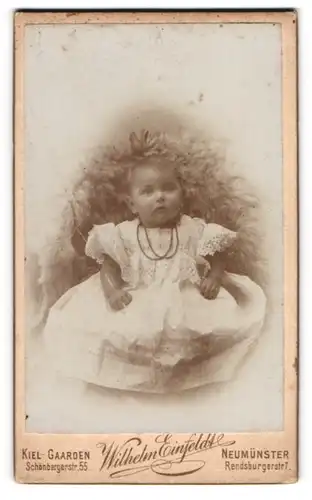 Fotografie Wilhelm Einfeldt, Kiel-Gaarden, Schönbergerstr. 55, Portrait niedliches Baby mit Halskette im Kleidchen