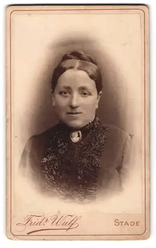 Fotografie Fridr. Wulf, Stade, Kl. Schmiedestrasse, Portrait hübsche Dame mit Flechtdutt und Brosche am Blusenkragen