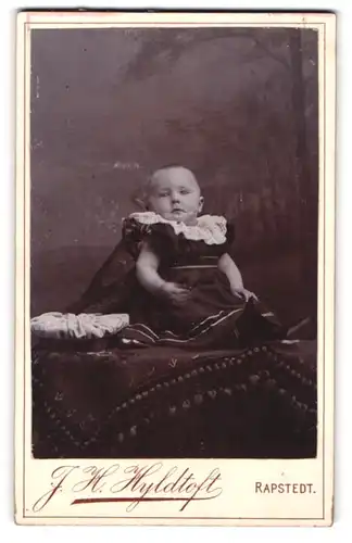 Fotografie J. H. Hyldtoft, Rapstedt, Portrait süsses Baby im Kleidchen mit Stickerei am Kragen