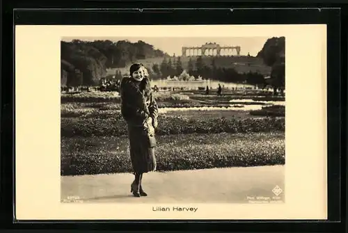 AK Schauspielerin Lilian Harvey im Pelzmantel in einer Parkanlage