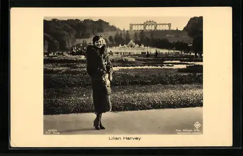 AK Schauspielerin Lilian Harvey im Pelzmantel in einer Parkanlage