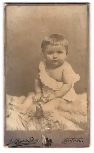 Fotografie Jean Baptiste Feilner, Oldenburg i. Gr., Rosenstr. 29, Süsses Kleinkind im Hemd sitzt auf Fell