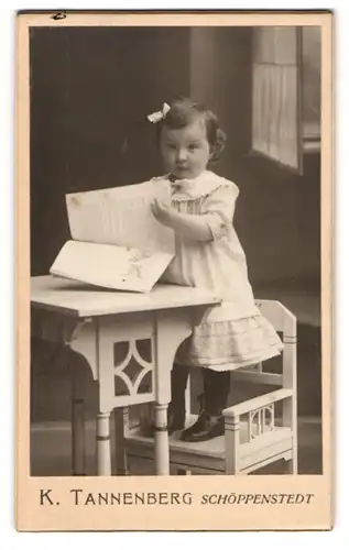 Fotografie K. Tannenberg, Schöppenstedt, Kleines Mädchen mit Haarschleife, auf einem Stuhl stehend
