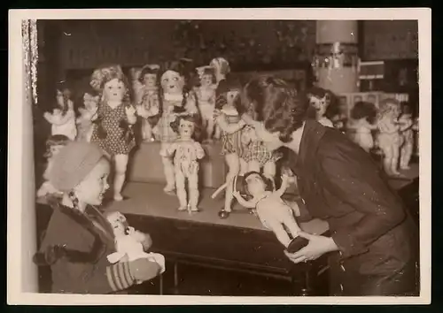 Fotografie Spielzeugwaren-Laden, fröhliches Mädchen erfreut sich an der Auswahl von Puppen, Puppe, Doll