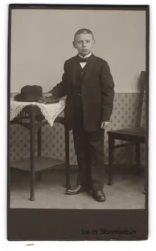 Fotografie Louis Schindhelm, Ebersbach i. S., junger Knabe im dunklen Anzug mot Hut und Bibel zu seiner Kommunion