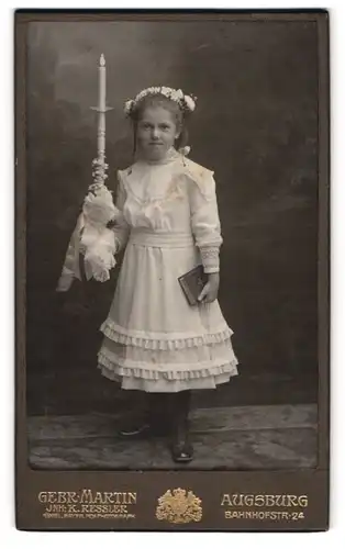 Fotografie Gebr. Martin, Augsburg, Portrait süsses kleines Mädchen zu ihrer Kommunion im weissen Kleid mit Kerze