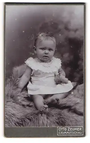 Fotografie Otto Zeumer, Crimmitschau, Jacobsgasse 14, Kleinkind im Spitzenkleidchen auf einem Fell
