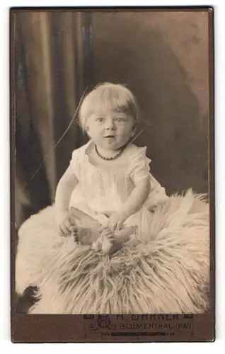 Fotografie Hans Ohrner, Blumenthal i /Han., Weserstr. 11, Süsses Kleinkind im Hemd sitzt auf Fell