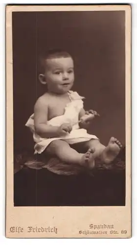 Fotografie Else Friedrich, Spandau, Schönwalder Strasse 89, Baby mit Rassel, auf einem Fell sitzend