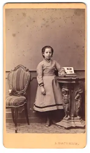 Fotografie L. Bachrich, Wien, Ferdinandsstr. 17, Portrait kleines Mädchen im grauen Kleid mit aufgeschlagenene Fotoalbum