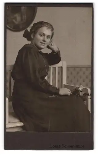 Fotografie Louis Schindhelm, Ebersbach i. S., Portrait Frau im schwarzen Kleid mit Haarschleife posiert im Atelier