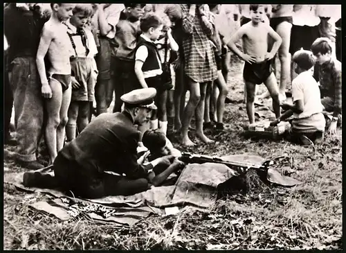 Fotografie DDR-Soldat bringt Kindern das Schiessen mit einem Gewehr bei