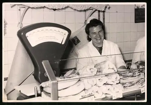 Fotografie Fleischfachverkäuferin neben Rückenfett hinter dem Verkaufstresen einer Fleischerei - Metzgerei