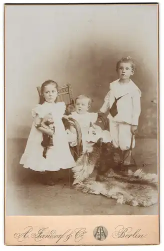 Fotografie A. Jandorf & Co., Berlin-NO, Grosse Frankfurterstr. 113, Hübsch gekleidetes Kinderpaar mit Puppe & Kleinkind